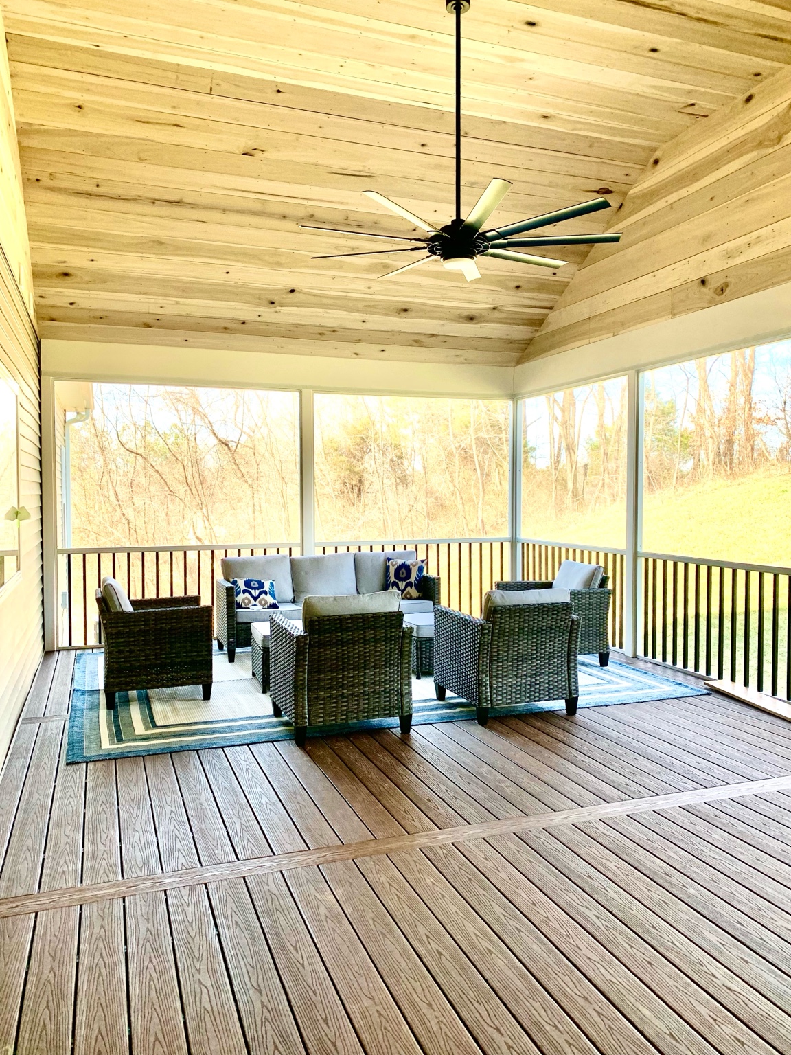 Screened-in porch with wicker seating and wood ceiling